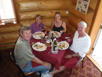 a group of people sitting around a table with food at Northern Rockies Lodge in Muncho Lake