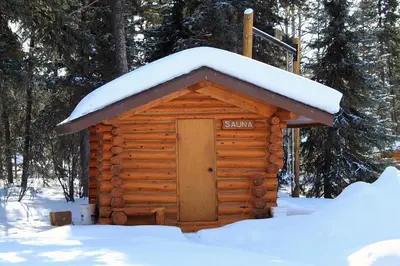 a log cabin with snow on top of it at Northern Rockies Lodge in Muncho Lake