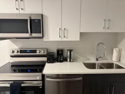 a kitchen with white cabinets and a stove and a sink at Peace Haven in Edmonton