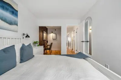 a white bedroom with a large bed with blue pillows at Peaceful DT Condo, Saddledome, HeatedParking in Calgary