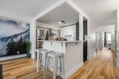 a kitchen with a counter and stools in a room at Peaceful DT Condo, Saddledome, HeatedParking in Calgary