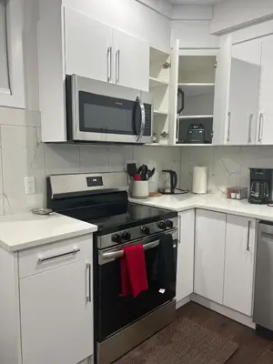 a kitchen with white cabinets and a stove with a microwave at Kizito in Edmonton