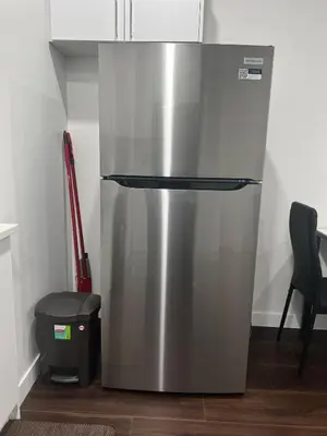 a stainless steel refrigerator in a kitchen with a trash can at Kizito in Edmonton