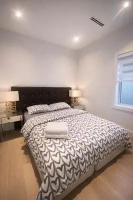 a bedroom with a large bed with a black and white blanket at Luxury & brand-new Cozy duplex in South Vancouver in Vancouver
