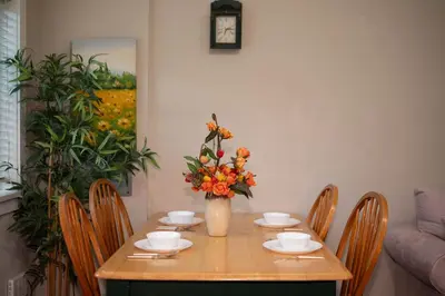 a dining room table with a vase of flowers on it at Cozy 3 BR Suite Ideal for Families and Groups in Vancouver
