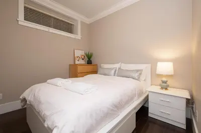 a white bedroom with a white bed and a window at Cozy 3 BR Suite Ideal for Families and Groups in Vancouver