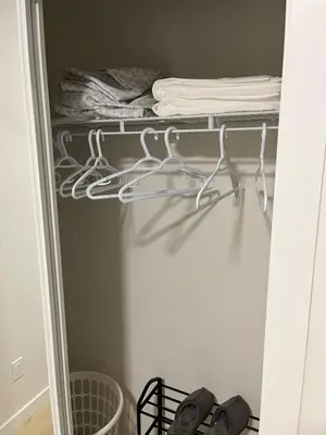 a closet with white hangers and towels on a shelf at cozy basement suite with 1-bed, wi-fi & Neflix in Edmonton