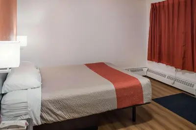 a small room with a bed and a red window at Motel 6-Fort St. John, BC in Fort Saint John