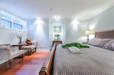 a bedroom with a large bed with a green stuffed animal on it at Luxury 1200 squft 2BR Shaughnessy Suite Near YVR & DT in Vancouver
