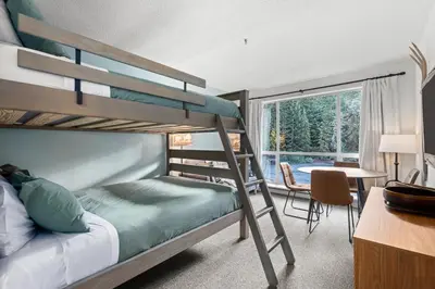 a bedroom with a bunk bed with a desk and a table at 1BR | Greystone Lodge | Ski in / Ski out | Pool & Hot Tub | Epic Locations in Whistler