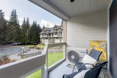 a balcony with chairs and a view of a house at 2BR + Sofa Bed | Greystone Lodge | Ski in / Ski out | Split home living | Pool & Hot Tub in Whistler