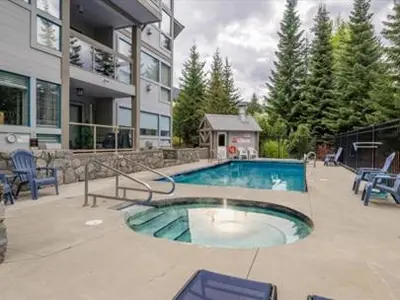 a swimming pool in front of a house at 2BR + Sofa Bed | Greystone Lodge | Ski in / Ski out | Split home living | Pool & Hot Tub in Whistler