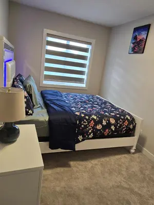 a bedroom with a bed and a window in a room at Cozy Comfort Homestaed-Near Airport in Calgary