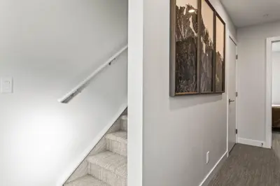 a white hallway with stairs and a painting on the wall at Cozy 3BR Mountainside Haven Near Banff in Canmore