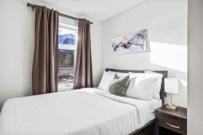 a bedroom with a white bed with a window at 3BR Rockies Haven Near Banff with Private Patio in Canmore