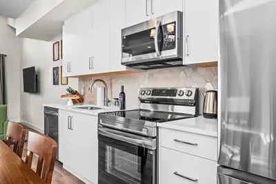 a kitchen with white cabinets and a stove top oven at 3BR Rockies Haven Near Banff with Private Patio in Canmore