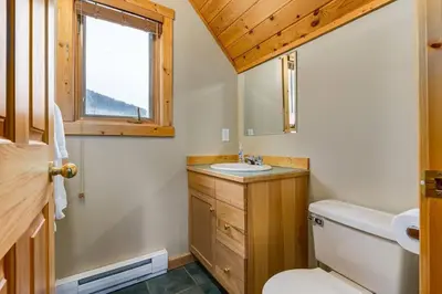 a bathroom with a toilet and a sink and a window at Beautiful Cottage In The Heart Of The Rockies in Golden