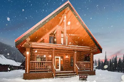 a log cabin in the snow with snow falling at Wonderful Rockies Cabin Getaway for Hike or Ski in Golden