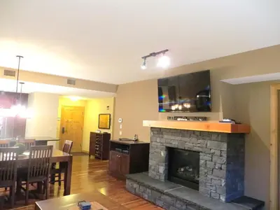 a living room with a fireplace and a dining room at Luxury Canmore Vacations in Canmore