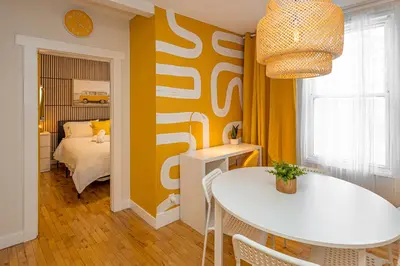 a dining room with a white table and a bedroom at Quiet Yellow Unit- Stampede, BMO, Nightlife Etc. in Calgary