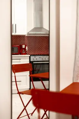 a red chair in a kitchen with a stove at Retro-Chic Hideaway - Walking Distance To Stampede in Calgary