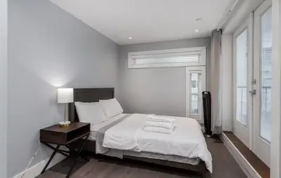 a white bedroom with a bed and a window at Large 3 Bedroom Laneway House in Vancouver