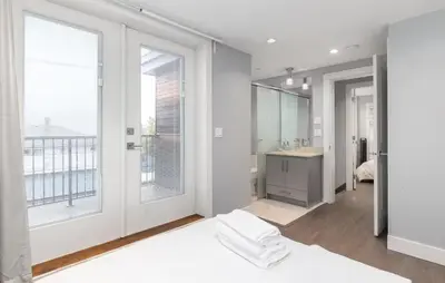 a white bathroom with a large window and a bed at Large 3 Bedroom Laneway House in Vancouver