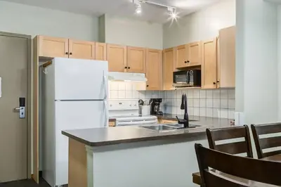 a kitchen with a white refrigerator and wooden cabinets at Heated Outdoor Pool Near Banff Park in Canmore