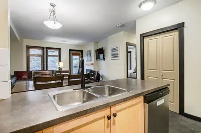 a kitchen with a sink and a living room at Heated Outdoor Pool Near Banff Park in Canmore