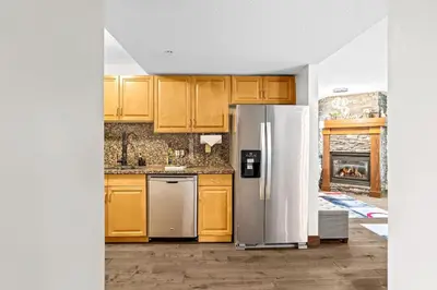 a kitchen with wooden cabinets and a stainless steel refrigerator at 2BR MTN Canmore Retreat with Private Balcony in Canmore