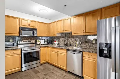 a kitchen with wooden cabinets and stainless steel appliances at 2BR MTN Canmore Retreat with Private Balcony in Canmore