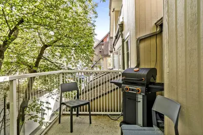 a grill and chairs on a balcony next to a building at 2BR MTN Canmore Retreat with Private Balcony in Canmore