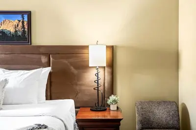 a hotel room with a bed and a lamp and a chair at Serene 2BR Solara Escape with BBQ Pool and Hot Tub in Canmore