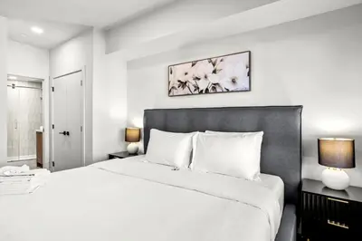 a white bedroom with a large bed and two lamps at 3BR Rockies Have Sleeps 8 with Hot Tub Pool and Mtn Views in Canmore
