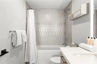 a white bathroom with a shower and a toilet at 3BR Rockies Have Sleeps 8 with Hot Tub Pool and Mtn Views in Canmore