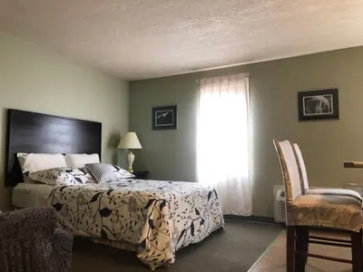a bedroom with a bed and a window and a chair at Eagles Nest Lodging in Hinton