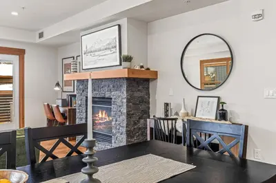 a living room with a fireplace and a dining room table at Luxury 1750sf Condo In DT Canmore Sleeps 10 in Canmore