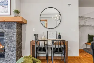 a living room with a table and chairs and a mirror at Luxury 1750sf Condo In DT Canmore Sleeps 10 in Canmore