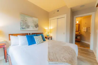 a bedroom with a large white bed with blue pillows at Corner Mountain View Retreat 2 Kings w Patio in Canmore