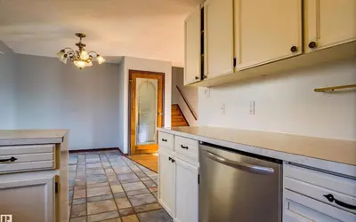 a kitchen with white cabinets and a stainless steel refrigerator at Fully furnished House near GrayNuns, Millwoods in Edmonton