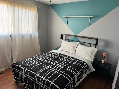 a bedroom with a black and white bed with a blue wall at Fully furnished House near GrayNuns, Millwoods in Edmonton