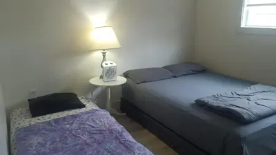 a bedroom with two beds and a table with a lamp at Vancouver Downtown Guest House- Walk to Skytrain & BC Place- Free Parking in Vancouver