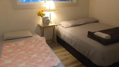 a bedroom with two beds and a table with a lamp at Vancouver Downtown Guest House- Walk to Skytrain & BC Place- Free Parking in Vancouver