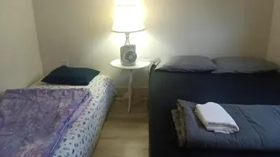 a bedroom with two beds and a table with a lamp at Vancouver Downtown Guest House- Walk to Skytrain & BC Place- Free Parking in Vancouver