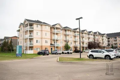 a large apartment complex with cars parked in a parking lot at Private room in Edmonton