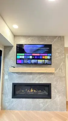 a fireplace with a flat screen tv on a wall at 3 Sisters Mountain Getaway | Luxe 2BR w Pool & Gym in Canmore