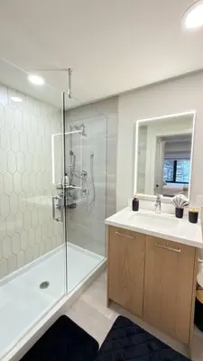 a bathroom with a shower and a sink and a mirror at 3 Sisters Mountain Getaway | Luxe 2BR w Pool & Gym in Canmore