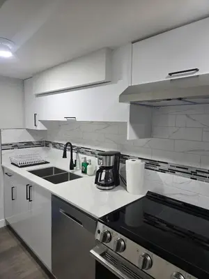 a white kitchen with a sink and a stove at Cozy Suite Near West Edmonton Mall in Edmonton
