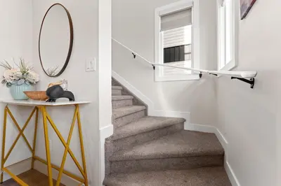a staircase in a house with a mirror and a table at Modern garden suite with parking in Edmonton