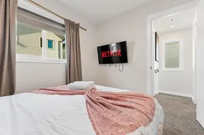 a bedroom with a bed and a tv on the wall at Modern garden suite with parking in Edmonton